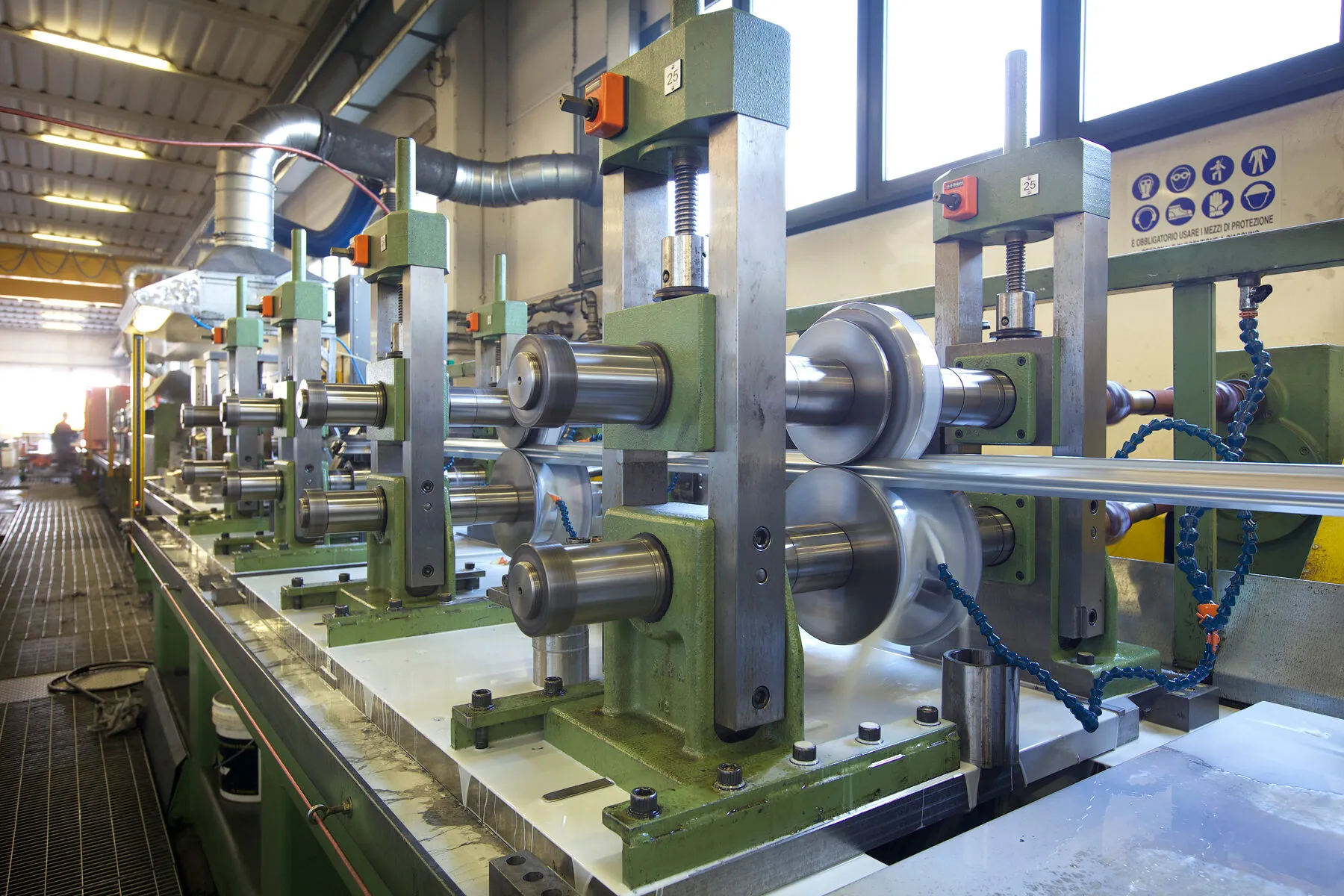 Steel strip passing through roller stations on a cold roll forming line